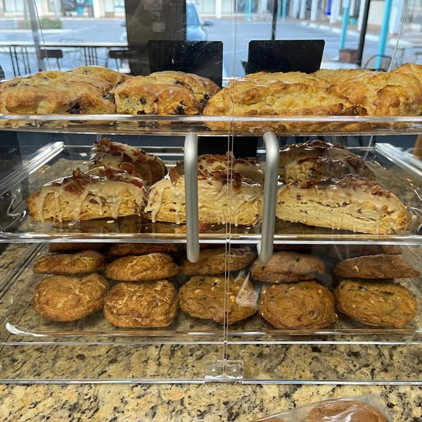 A display case at Liza's Kitchen filled with scones and cookies, with a street view in the background.
