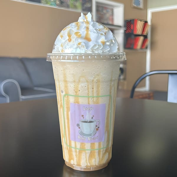 Liza's Kitchen's caramel frappe with whipped cream and caramel drizzle on a black table.