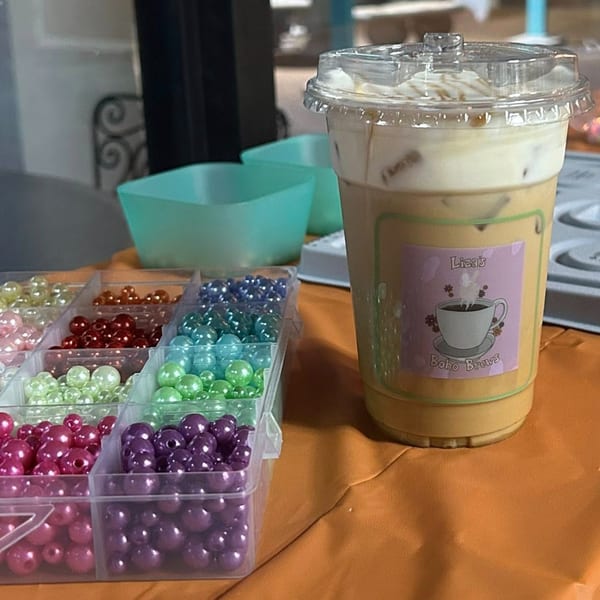 Iced coffee from Liza's Boho Brews next to colorful beads on an orange tablecloth.